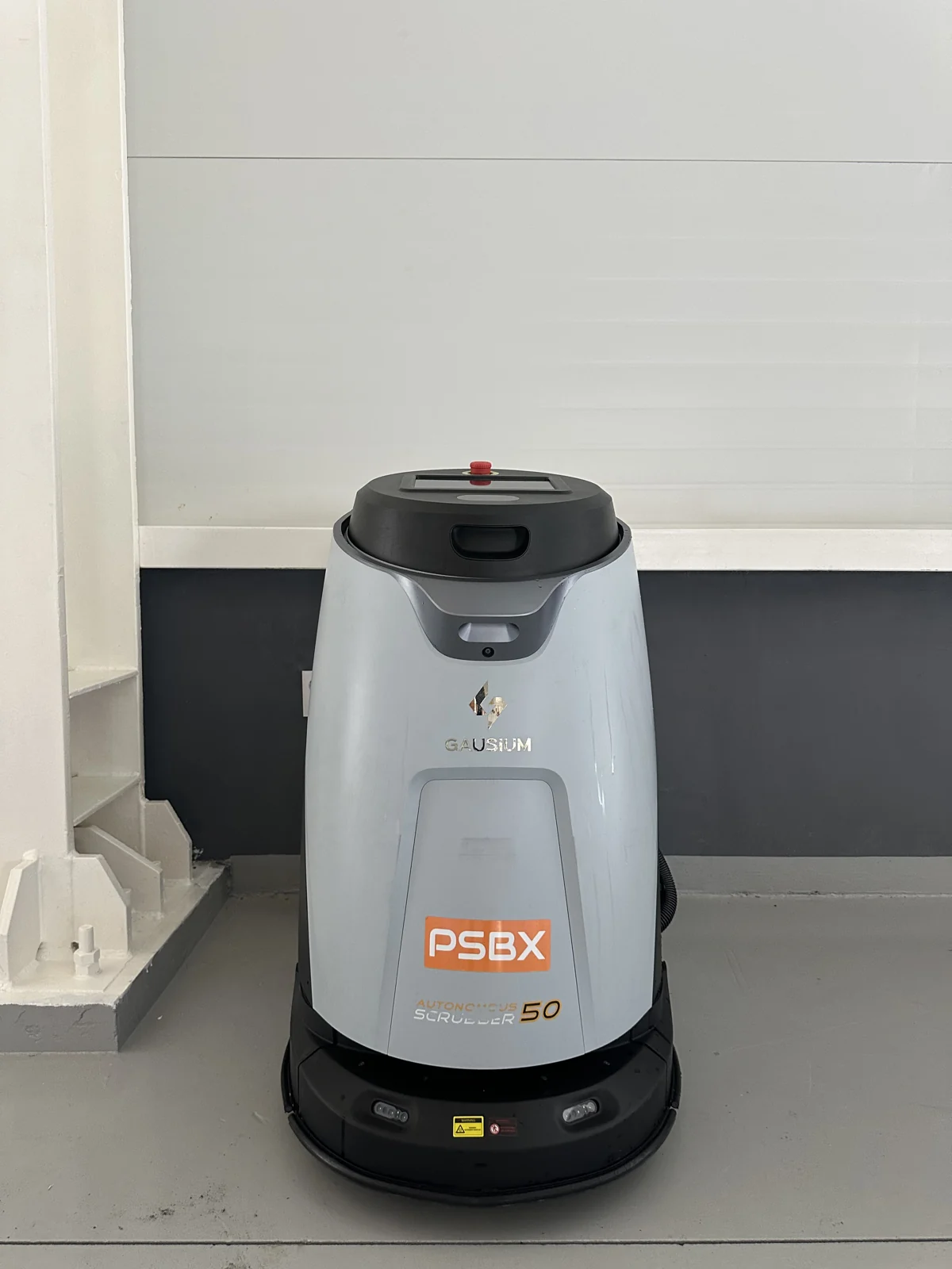 기둥 옆에 놓인 Gausium Scrubber 50 본체. 전면에 Scrubber 50과 PSBX 표기가 보입니다.